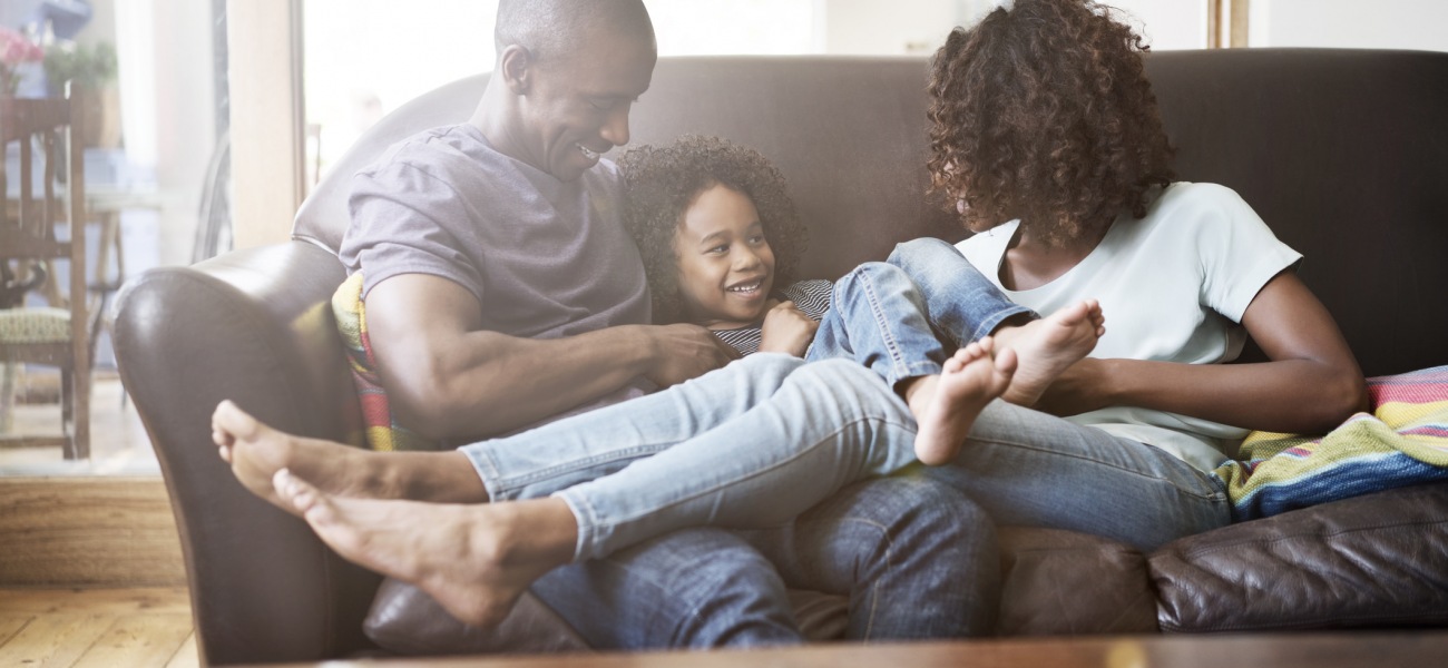 young family of three sitting on their couch